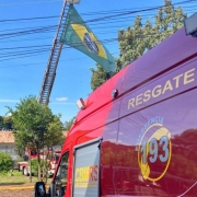Foto com uma ambulância do Corpo de Bombeiros e a bandeira do Brasil ao Fundo